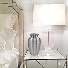 pewter adult urn for human ashes on glass table in bedroom